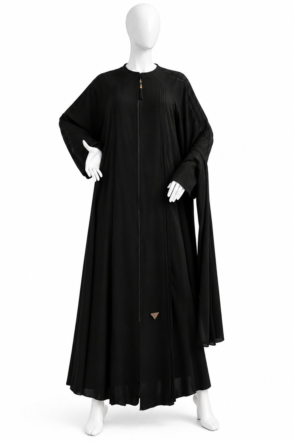 A mannequin displaying a black burqa, with the garment hanging from the neck without any visible fasteners, set against a plain background with a shadow of a palm leaf on the wall.