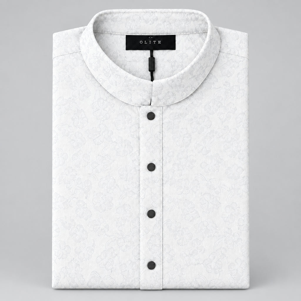 A folded cream-colored shirt with a light gray monogram pattern, featuring a mandarin collar and three dark buttons, displayed on a gray surface.