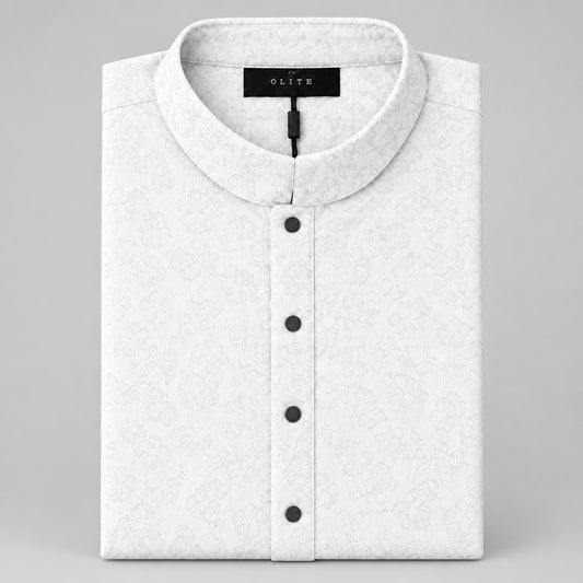 A folded cream-colored shirt with a light gray monogram pattern, featuring a mandarin collar and three dark buttons, displayed on a gray surface.