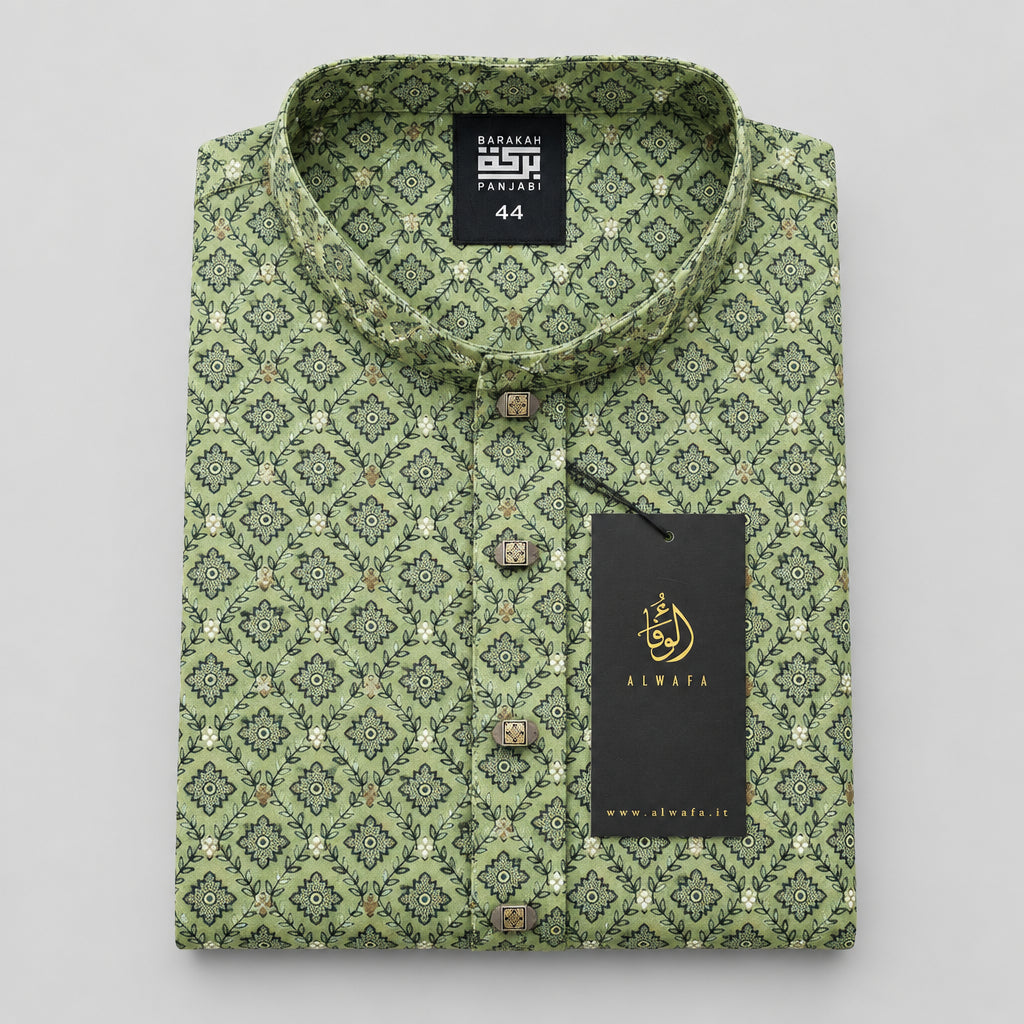 A folded men's shirt with a green and beige geometric pattern, displayed on a light wood table. The shirt features a band collar, button-down front, and a black hangtag with the brand name 'KINSHA'.