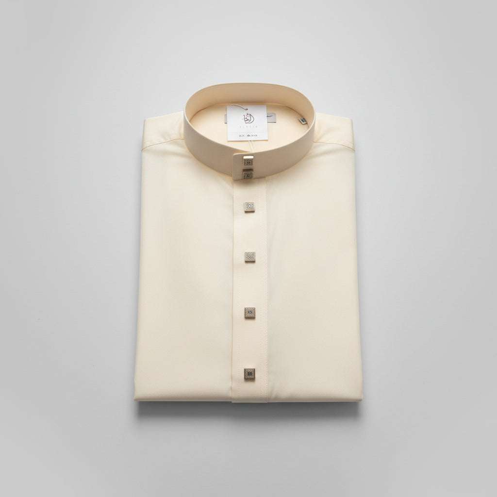 An off-white/cream traditional long-sleeve shirt with a high stand-up collar and a vertical button placket, laid flat on a light wood surface.