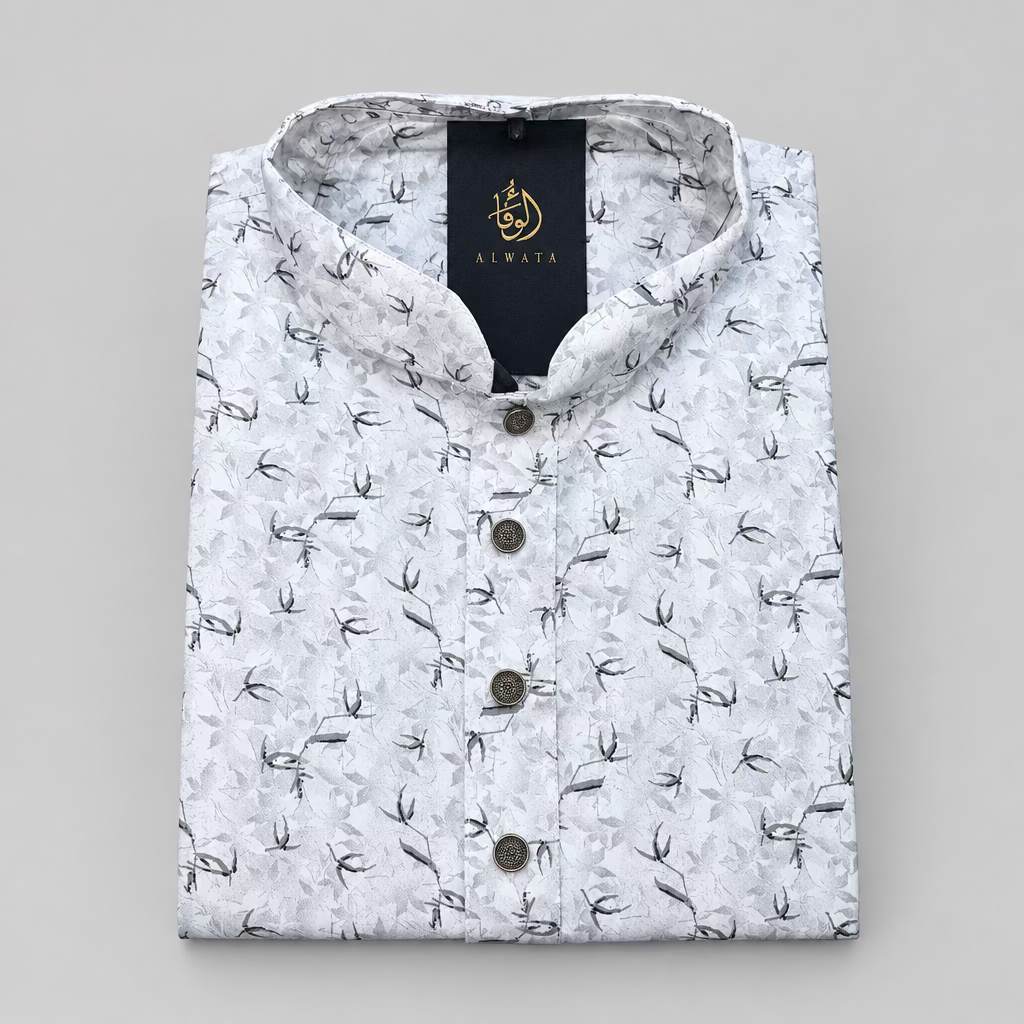 A folded white long-sleeve kurta with a black leaf pattern, featuring a mandarin collar and a black brand label with gold lettering.