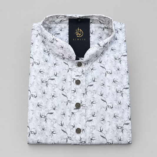A folded white long-sleeve kurta with a black leaf pattern, featuring a mandarin collar and a black brand label with gold lettering.