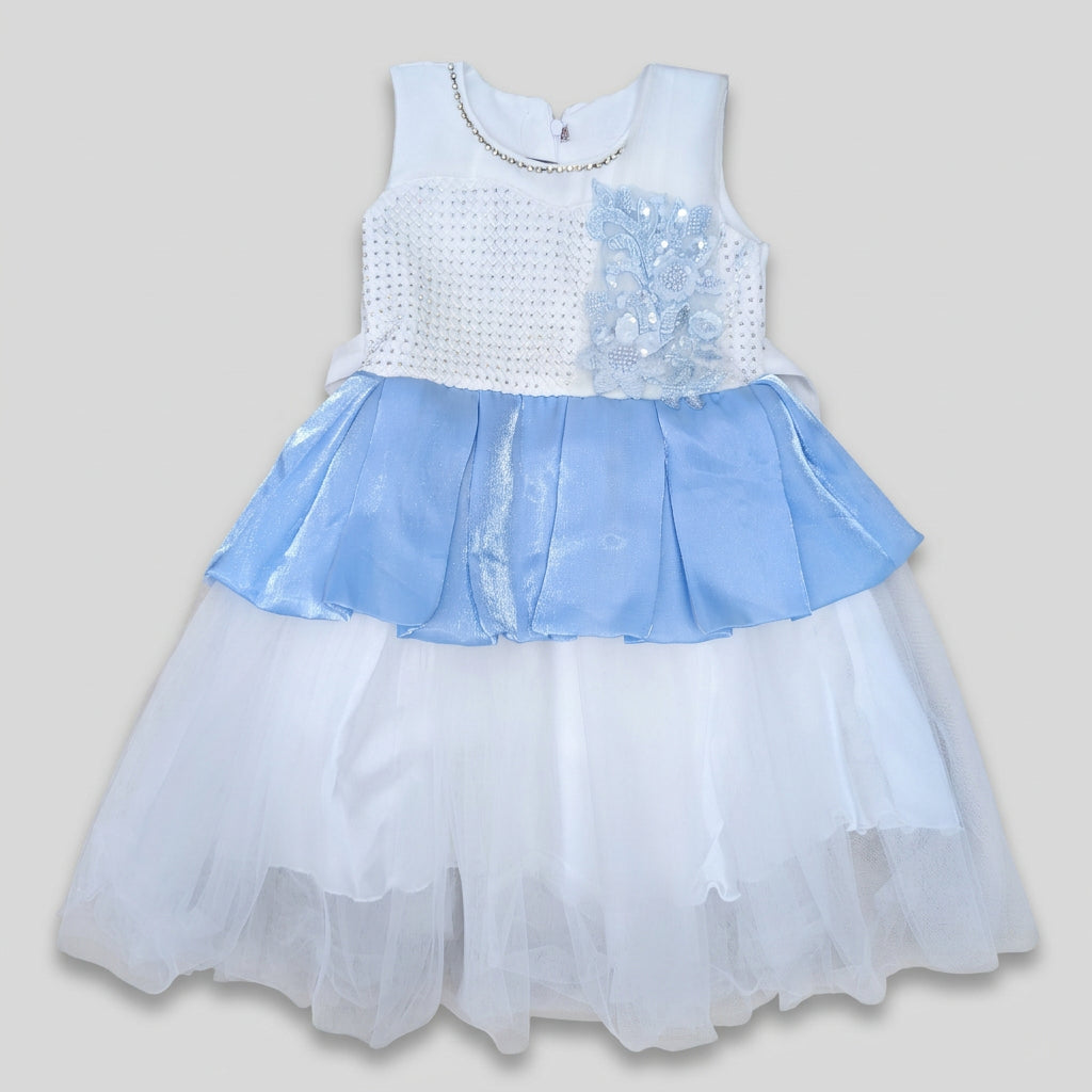 A sleeveless girls' party dress with a white textured bodice, a light blue ruffled overlay, and a layered white tulle skirt, laid flat on a cardboard background.