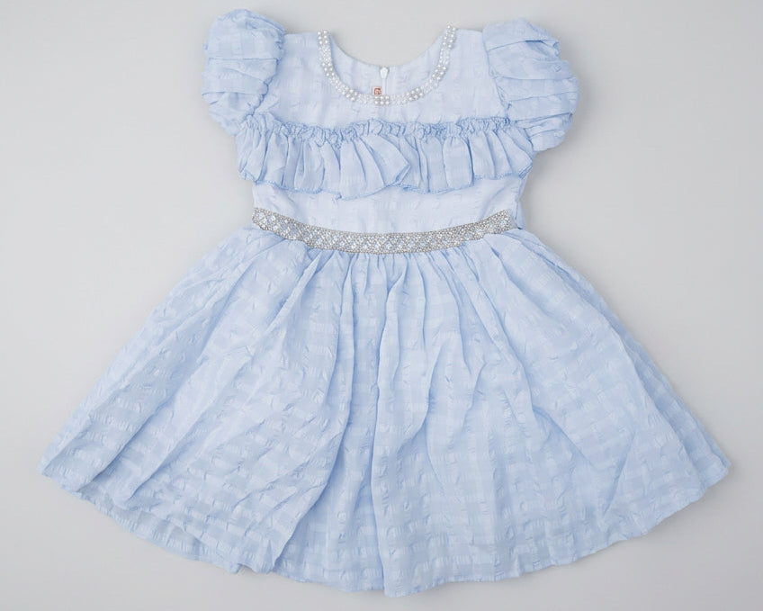 A light blue baby girl's dress with puffed sleeves, a smocked bodice, and a flared skirt, laid flat on a brown cardboard box.