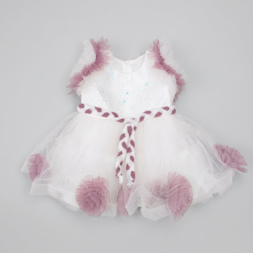 A white tutu dress with dusty purple ruffle accents and a matching braided headband, laid flat on a brown cardboard background.